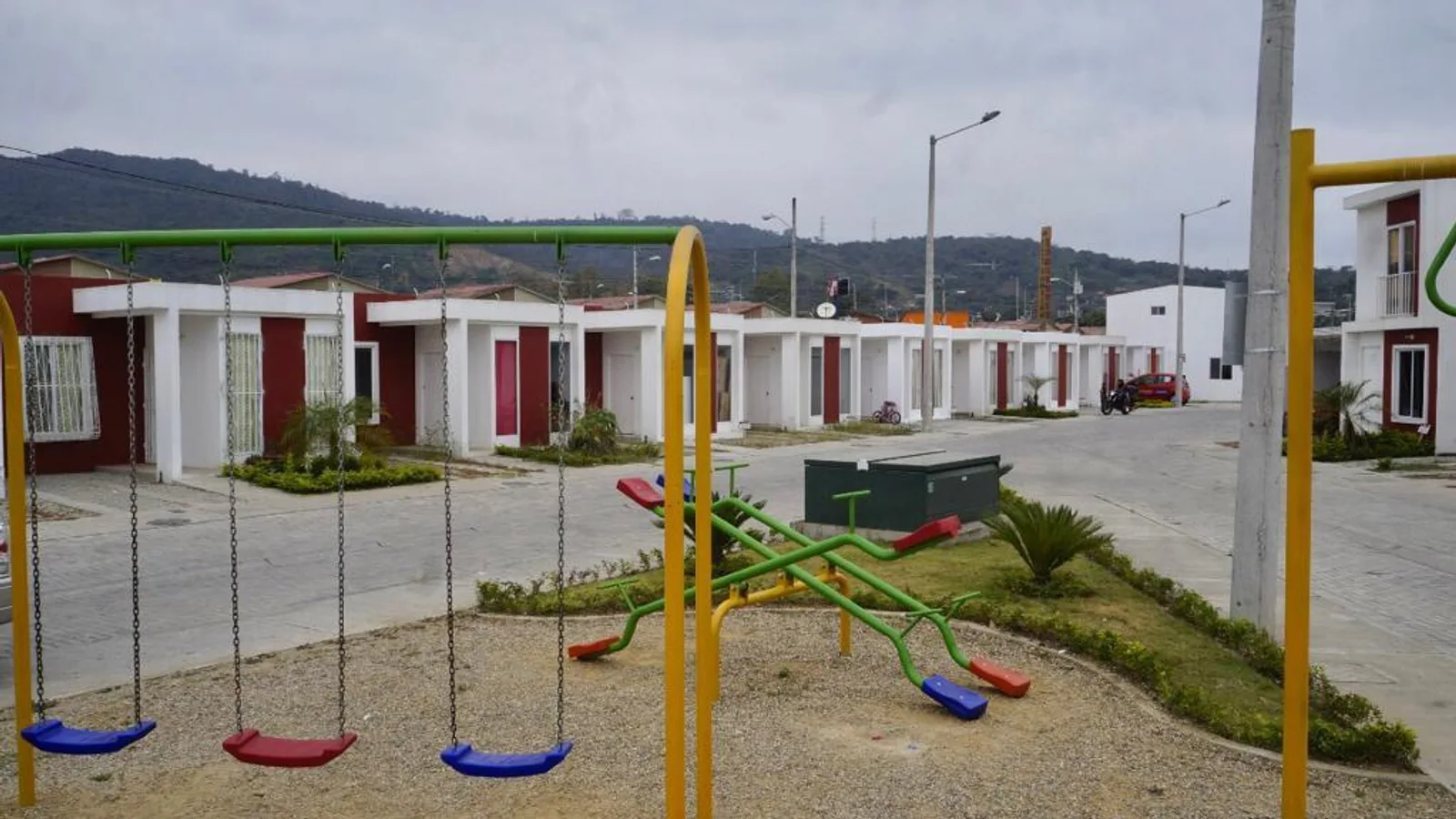 Calle con casas terminadas y vehículos de sus familias